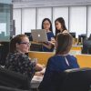 A lively office environment with four colleagues engaging in a collaborative discussion.