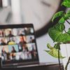 Laptop screen displaying a virtual group meeting next to a vibrant green plant, symbolizing the cost-efficiency of digital collaboration.